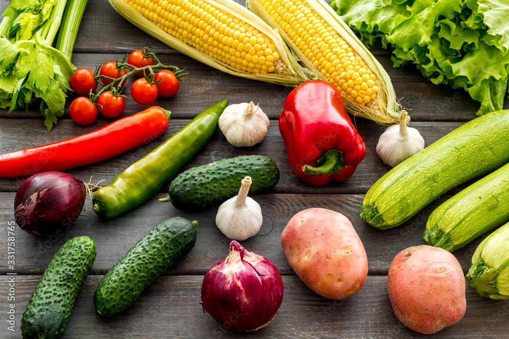 Fresh vegetables still life. Potato, cucumber, beet carrot, greenery on dark wooden background