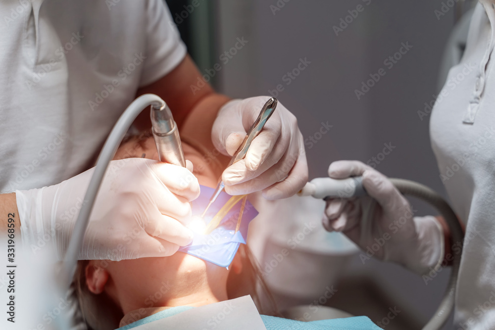 Dentist drilling tooth of a young patient. Real people. Selective focus. Closeup.