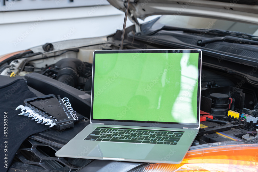 Laptop computer on car hood for engine diagnostic.