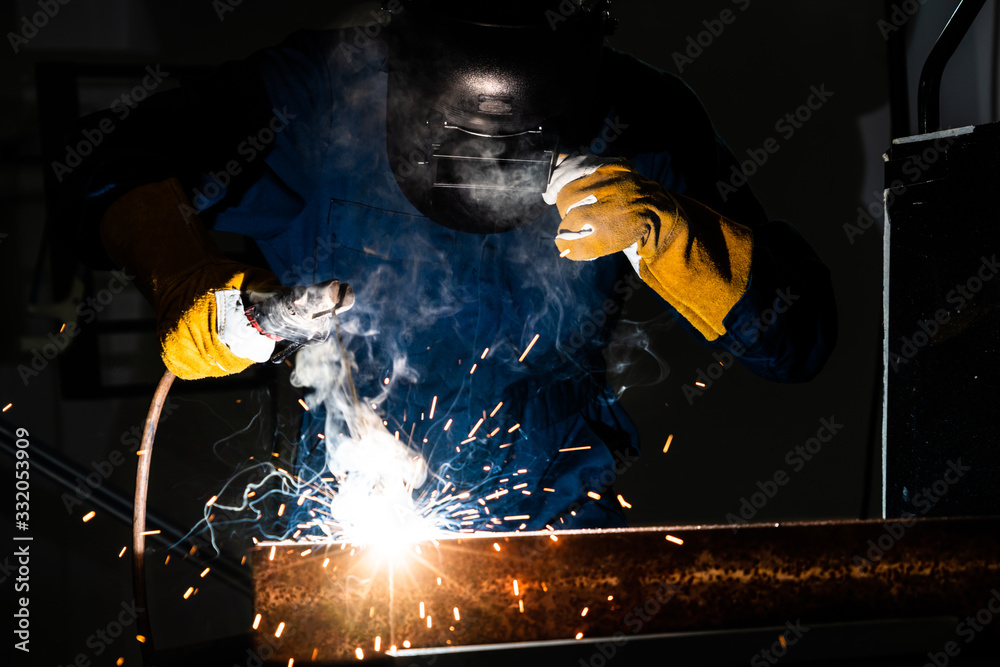 Metal welder working with arc welding machine.