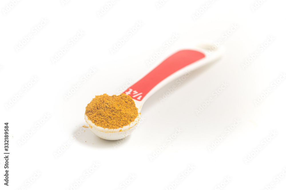 Curry Powder into a teaspoon. Measuring spoon on white background