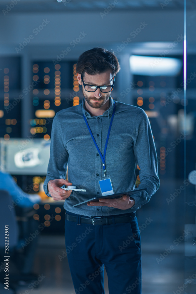 In Technology Research Facility: Chief Engineer Stands in the Middle of the Lab, Uses Tablet Compute