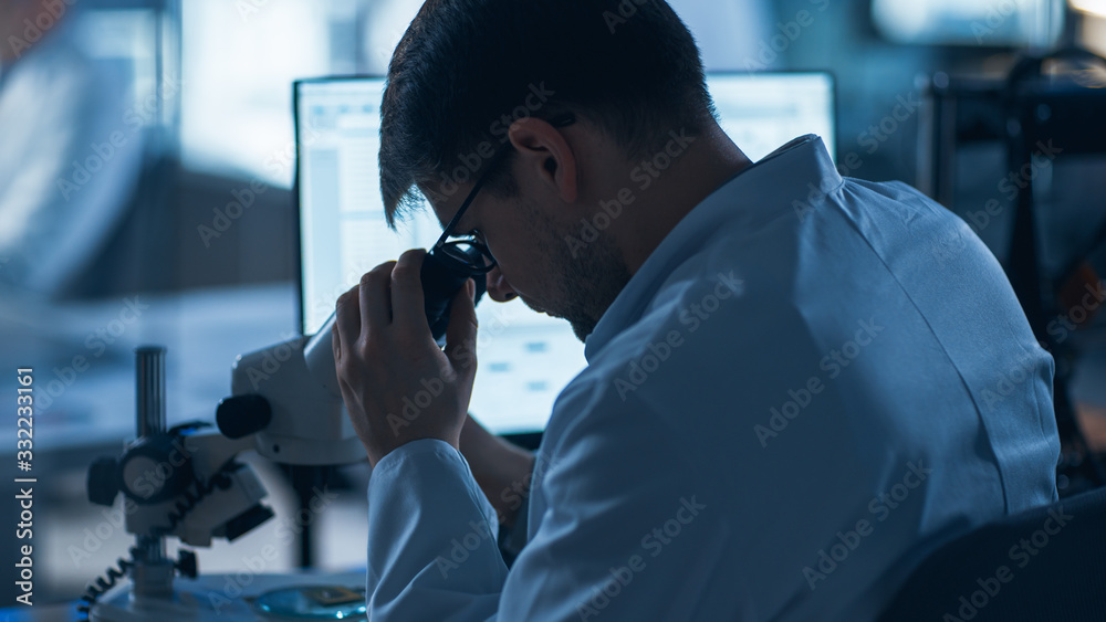 Shot of a Male IT Scientist Uses Computer with Electronic Microscope. In the Background Technology D