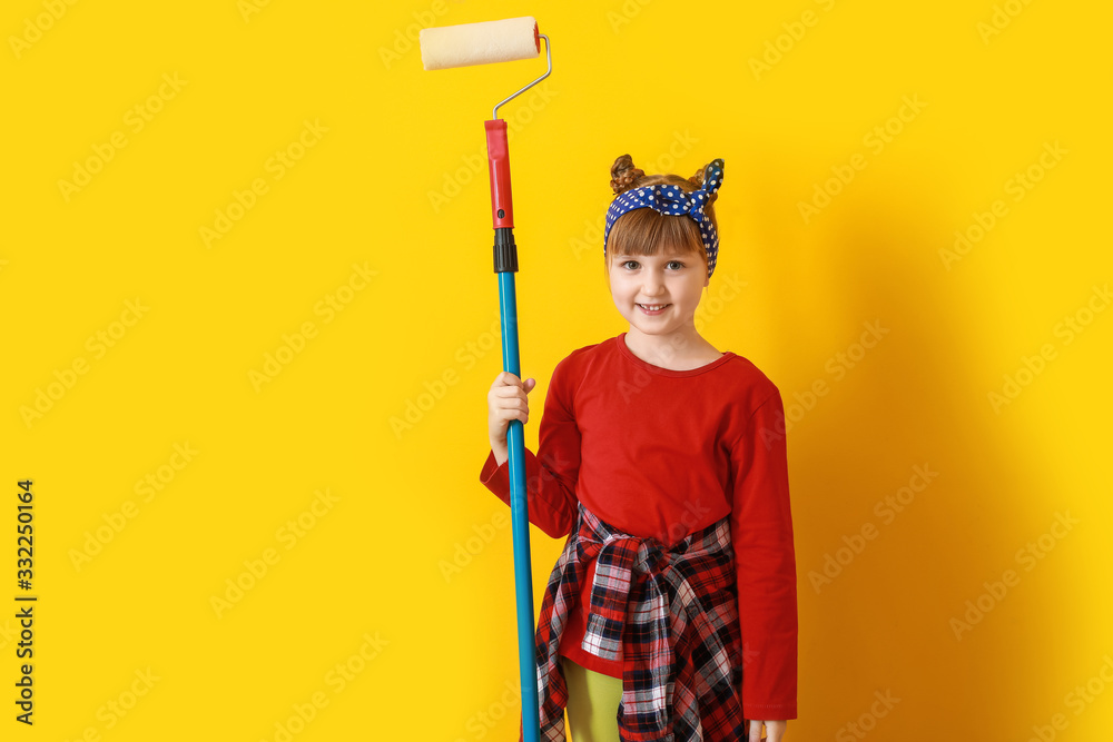 Little girl with paint roller near color wall