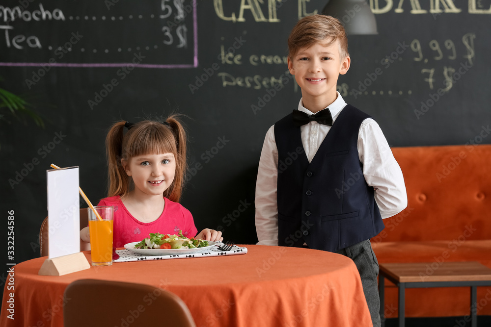 Cute little waiter and client in restaurant