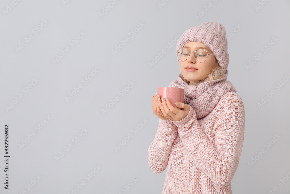 Beautiful young woman with cup of tea on grey background