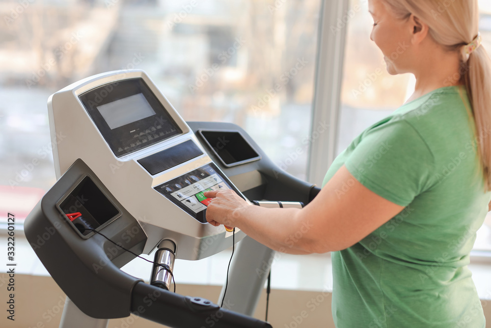 Sporty mature woman on treadmill in gym