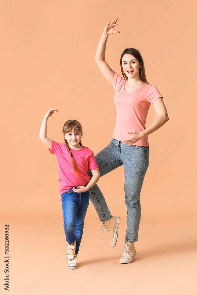 Happy mother and her little daughter dancing against color background