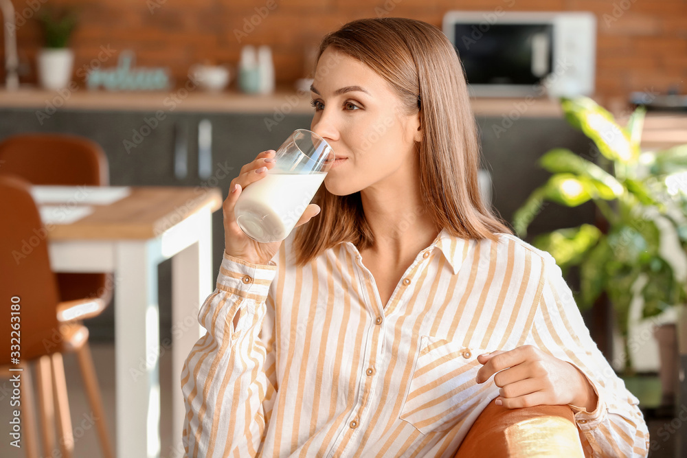 Beautiful young woman drinking milk at home