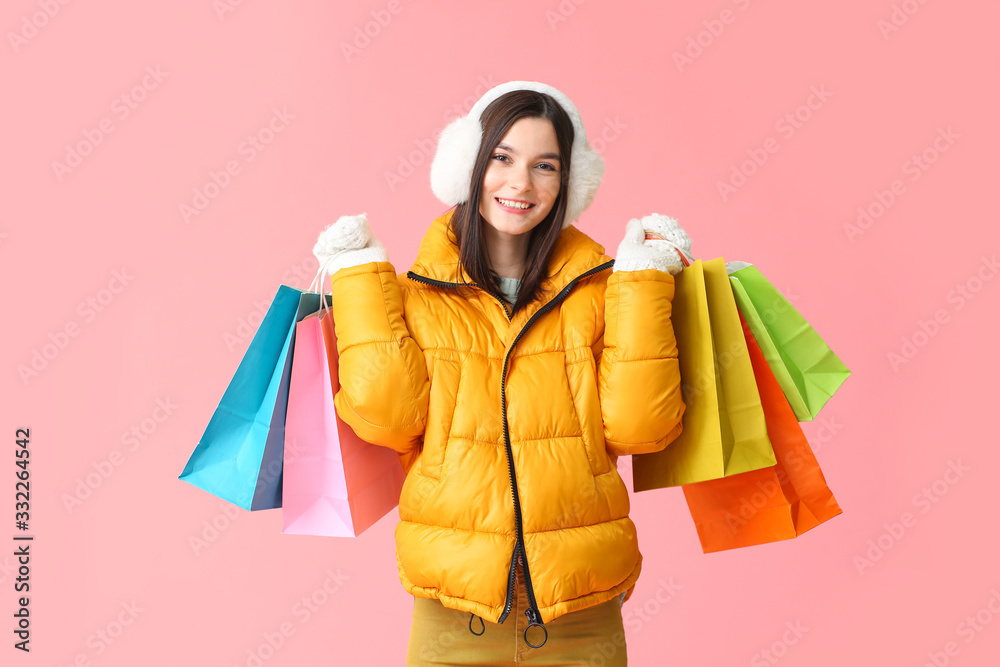 Beautiful young woman with shopping bags on color background