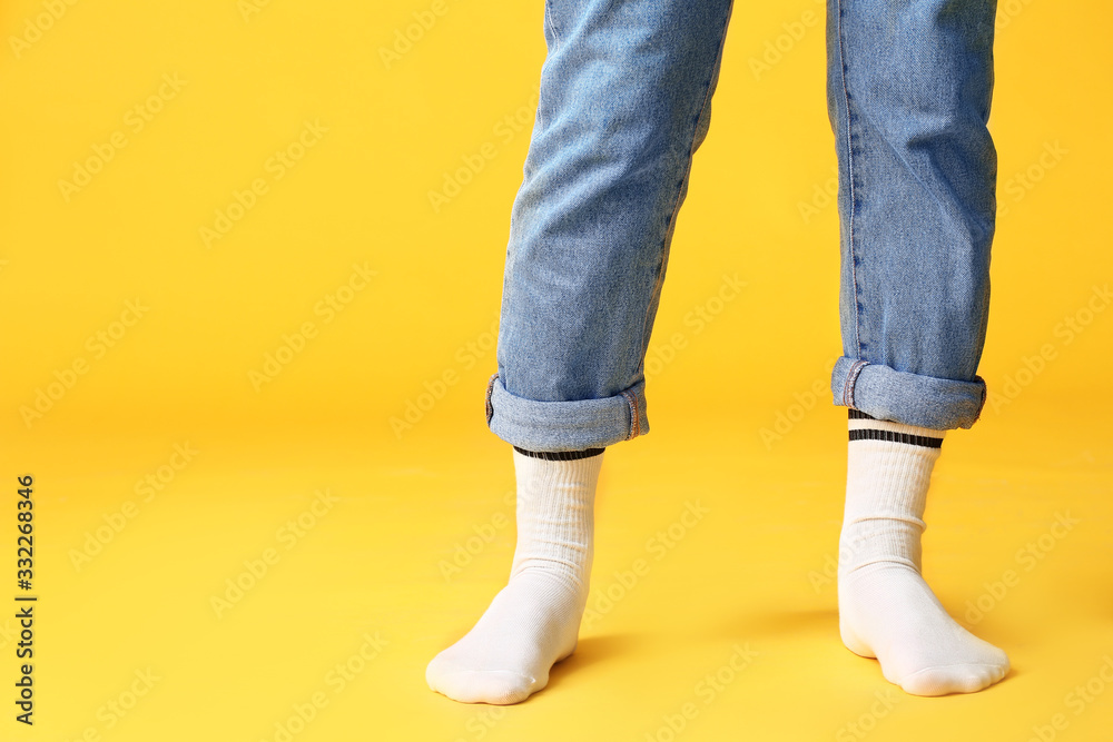 Male legs in socks and jeans on color background