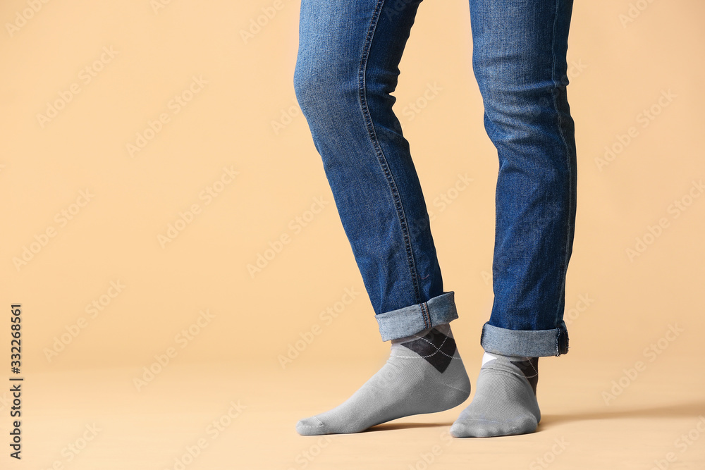 Male legs in socks and jeans on color background