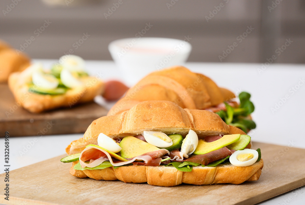 Tasty croissant sandwich on table in kitchen