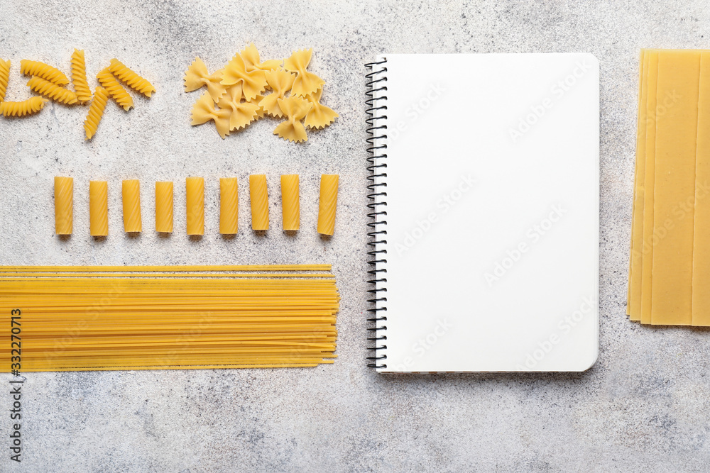 Cook book with dry pasta on grey background