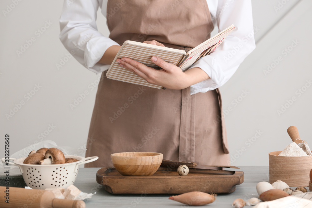 拿着烹饪书的女人在厨房准备食物