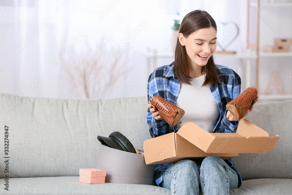 Young woman unpacking parcels with new clothes at home