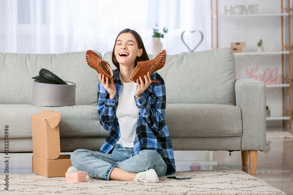 Young woman unpacking parcels with new clothes at home