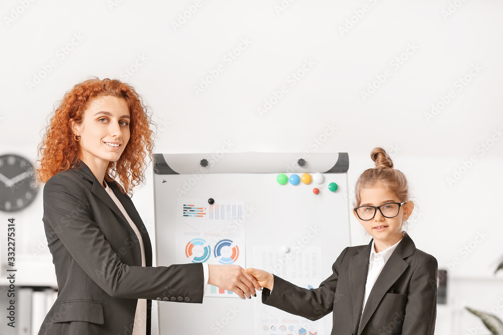 Little businesswoman with client shaking hands in office