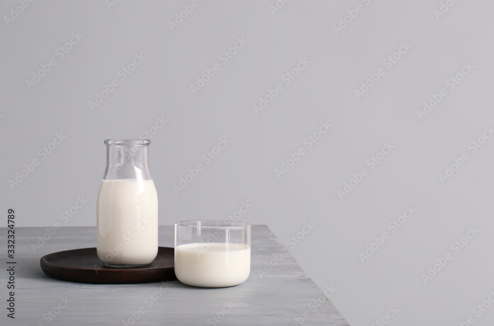 Glassware with fresh milk on table against grey background