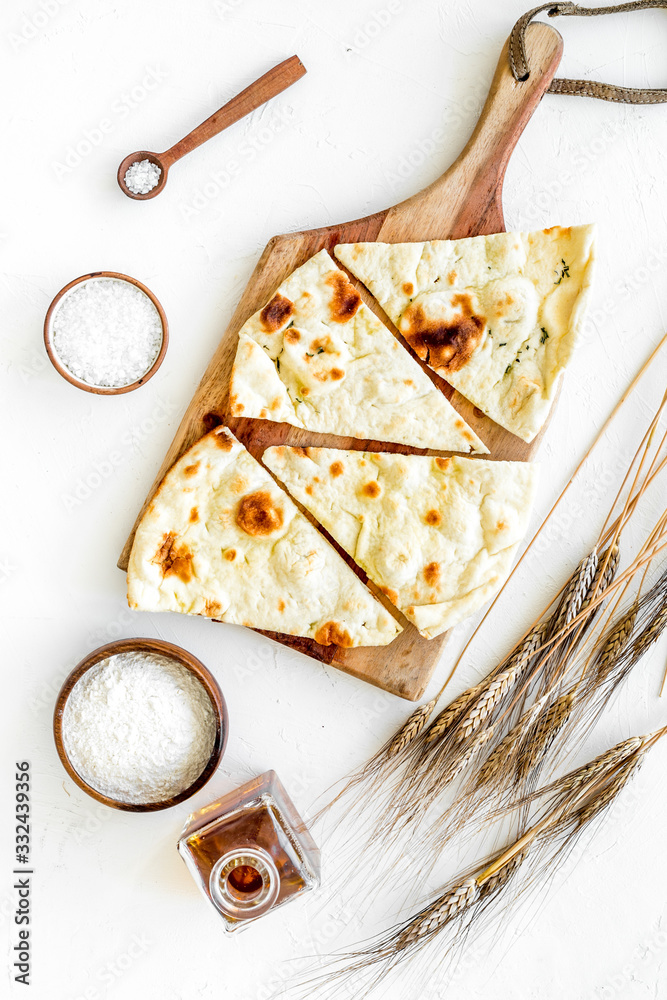 Focaccia ingredients. Wheat ears, flour, oil near bread on white background top-down