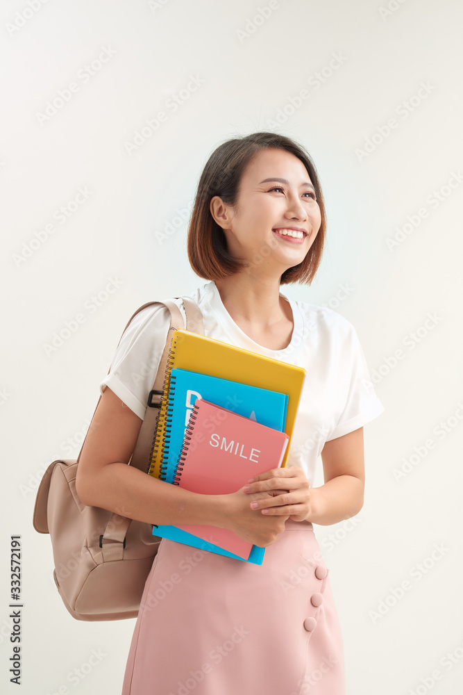 背着背包的年轻亚洲女学生拿着隔离在白色背景上的书工作室肖像