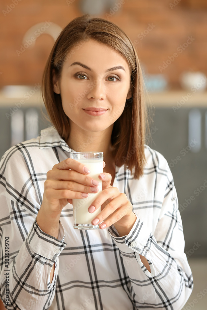 美丽的年轻女人在家喝牛奶