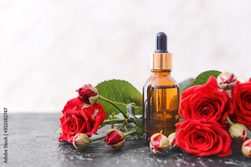 Bottle with rose essential oil on table