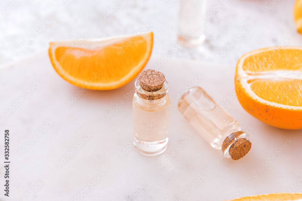 Bottles with orange fruit essential oil on table