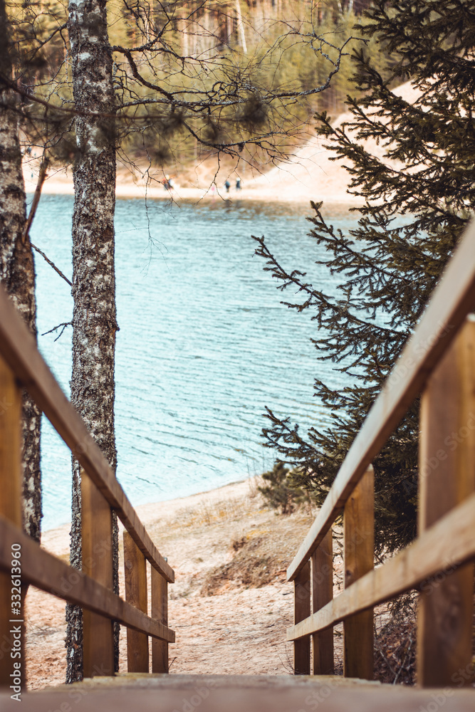 Wooden staircase with trees and a lake in background. Sandy beach.  Moody calm tones. Located in Dub