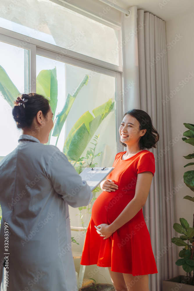 Doctor talks with the pregnant woman near window