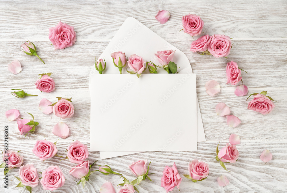 Blank envelope with rose flowers on wooden background. Top view of pink roses and rosebuds. Happy Mo