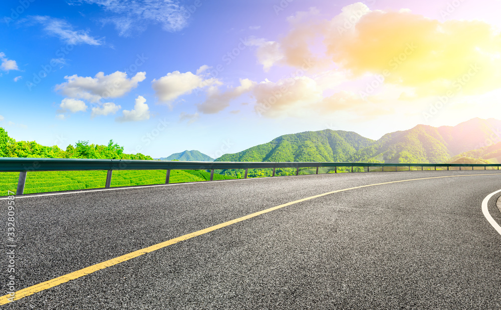 Asphalt road and green mountain nature landscape at sunset.