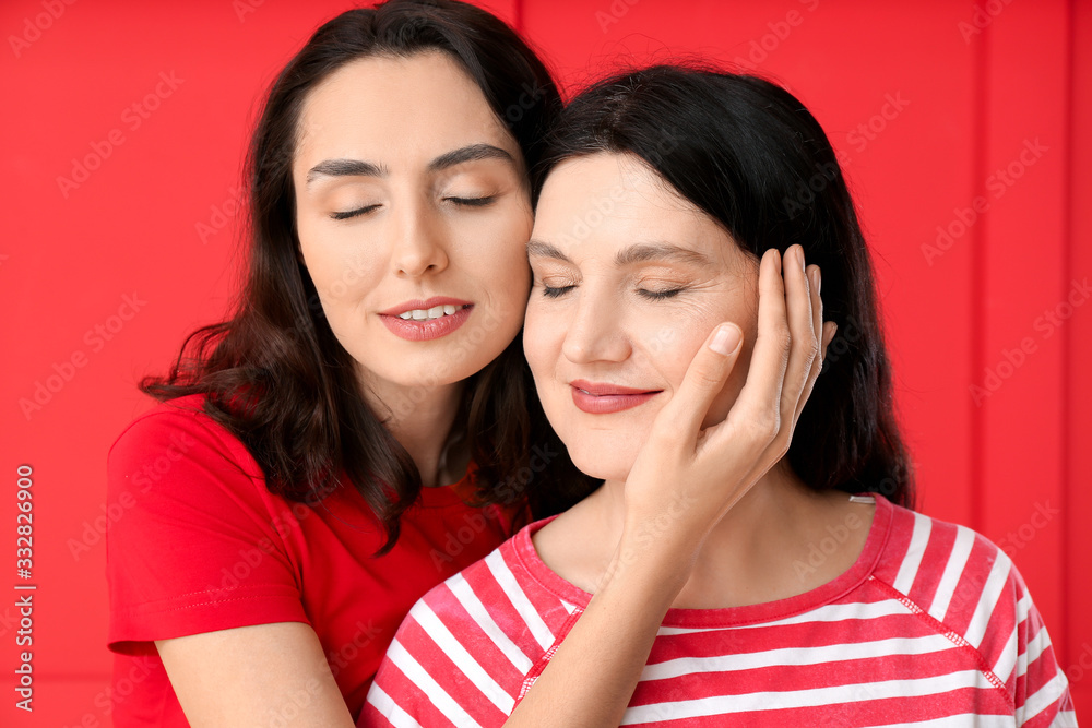 Portrait of adult daughter and her mother on color background