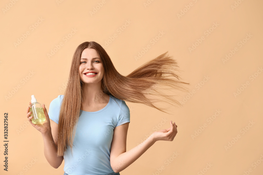 Beautiful young woman with hair spray on color background