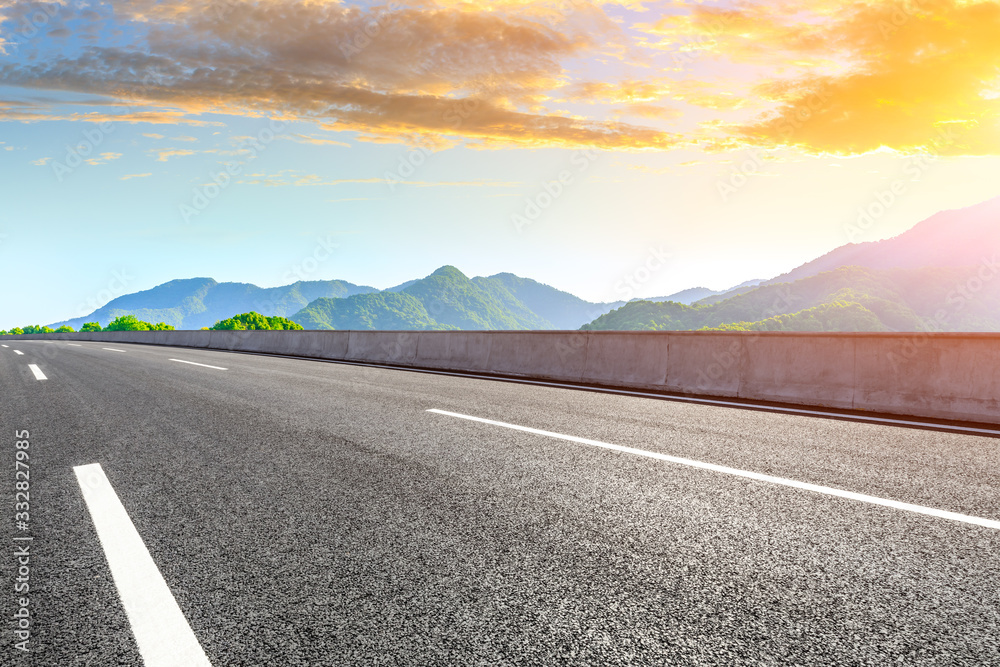 Empty asphalt road and green mountain nature landscape at sunset.