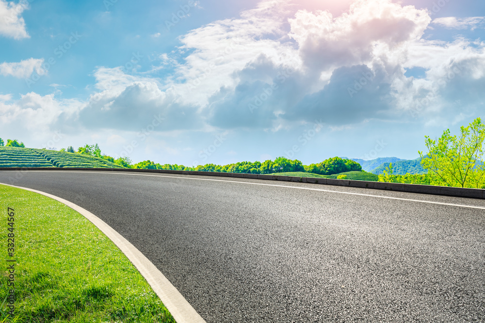 Asphalt road and green mountain nature landscape on sunny day.