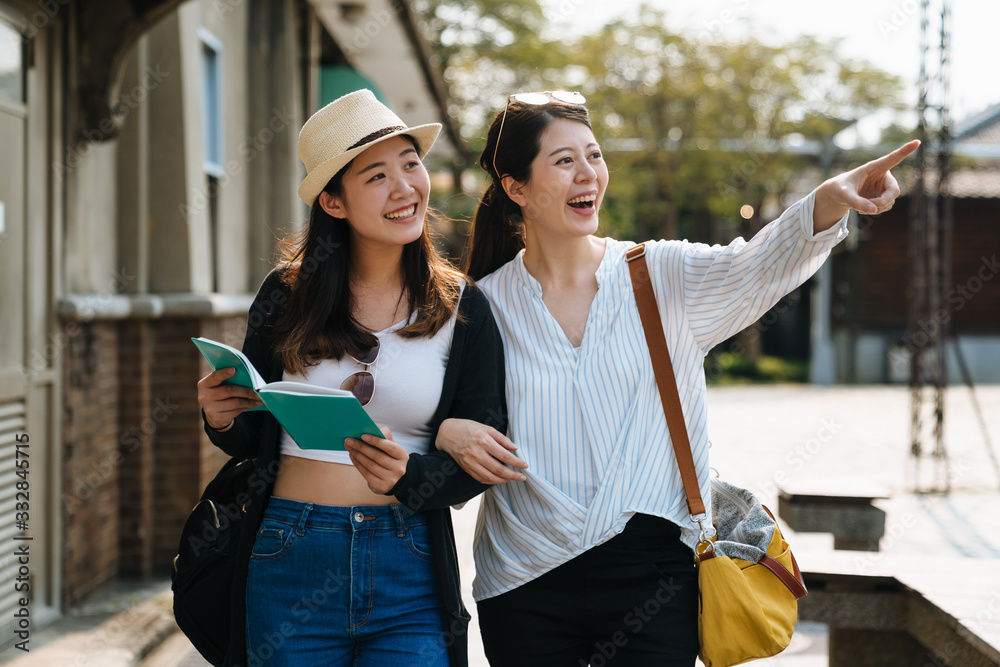 两个快乐的游客女性朋友带着导游书在暑假旅行。一群快乐的娘娘腔