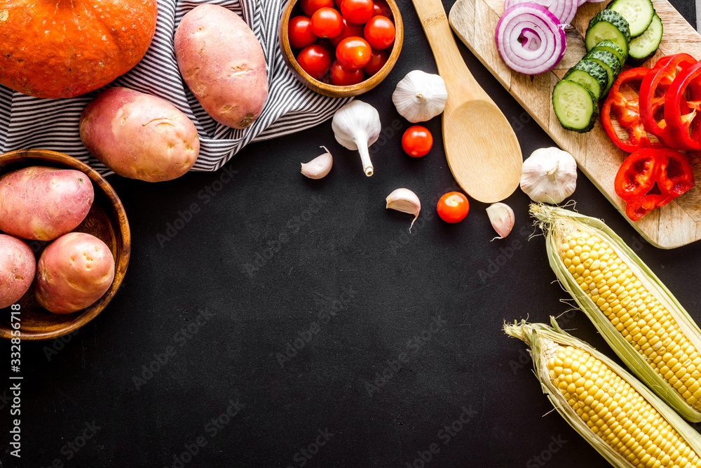 Autumn harvest. Vegetables - potato,cucumber, corn, greenery - frame on black background top-down co