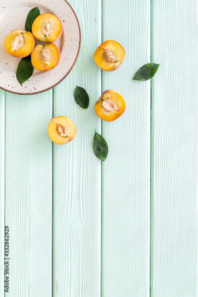 Healthy food. Ripe sliced peaches on plate on green wooden table top-down copy space