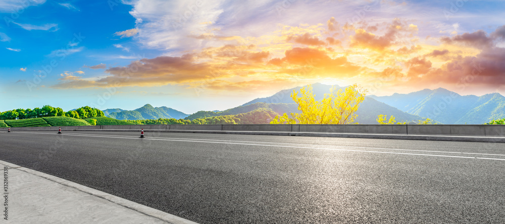 Asphalt road and green mountain nature landscape at sunset.