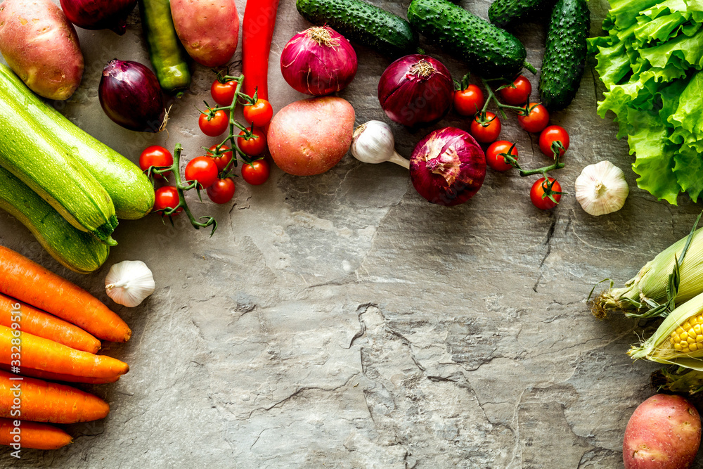 Set of autumn vegetables - potato, cucumber, carrot, greenery - on grey background top-down copy spa