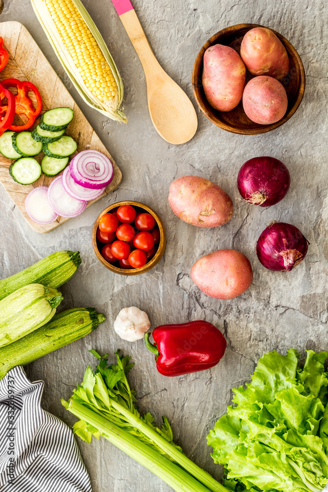 Autumn harvest. Vegetables - potato,cucumber, corn, greenery - on light stone background top-down