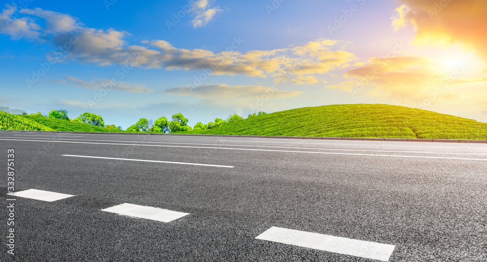 Asphalt road and green mountain nature landscape at sunset.