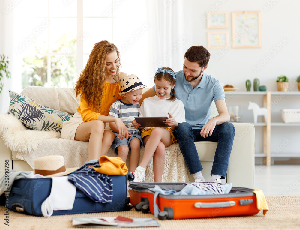 Excited family using tablet on sofa while packing for journey.