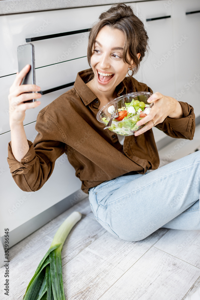 年轻女子在家里的厨房里与健康沙拉自拍。健康e