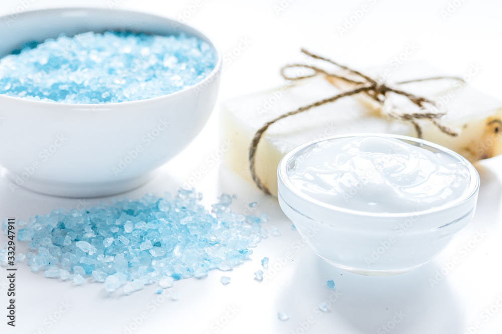 Home cosmetic with cream and blue sea salt on white background