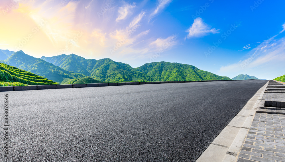 空旷的柏油路和日落时的青山自然景观。