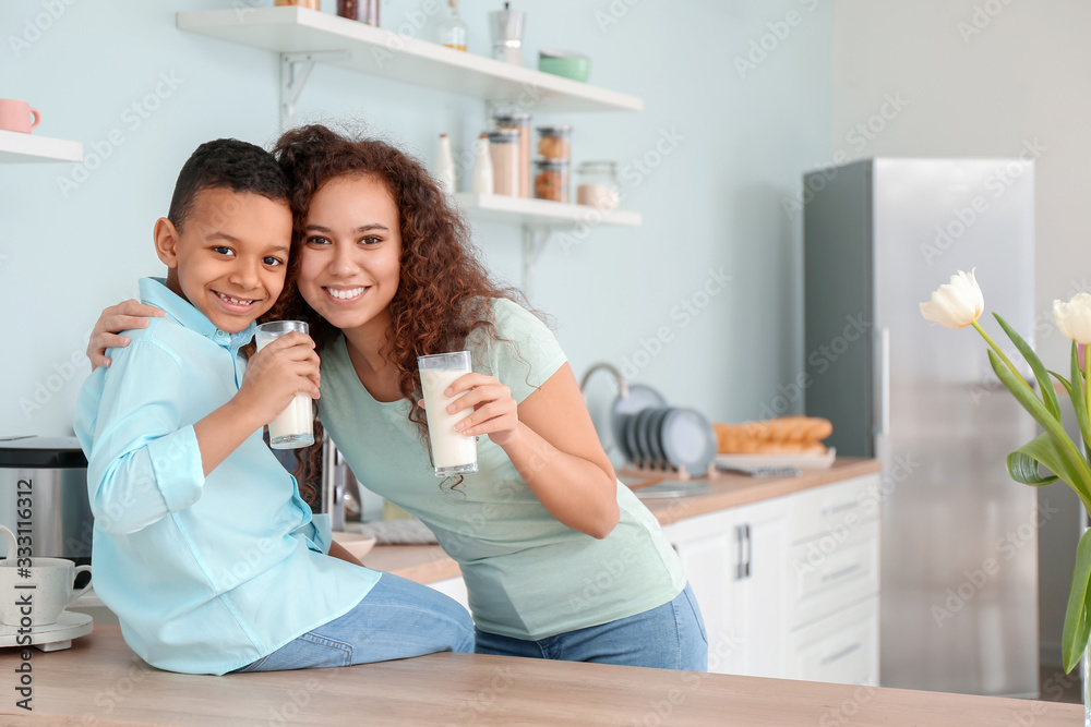 African-American woman and her son drinking milk in kitchen