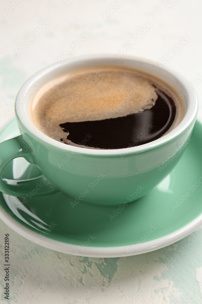 Cup of hot coffee on light background