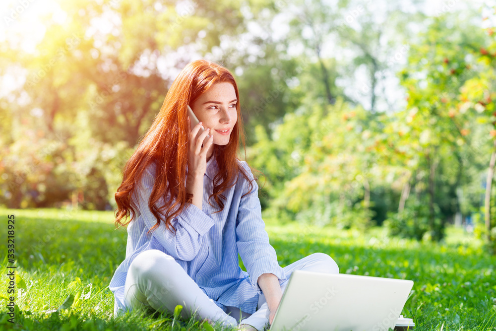 Young redhead woman sitting on green grass